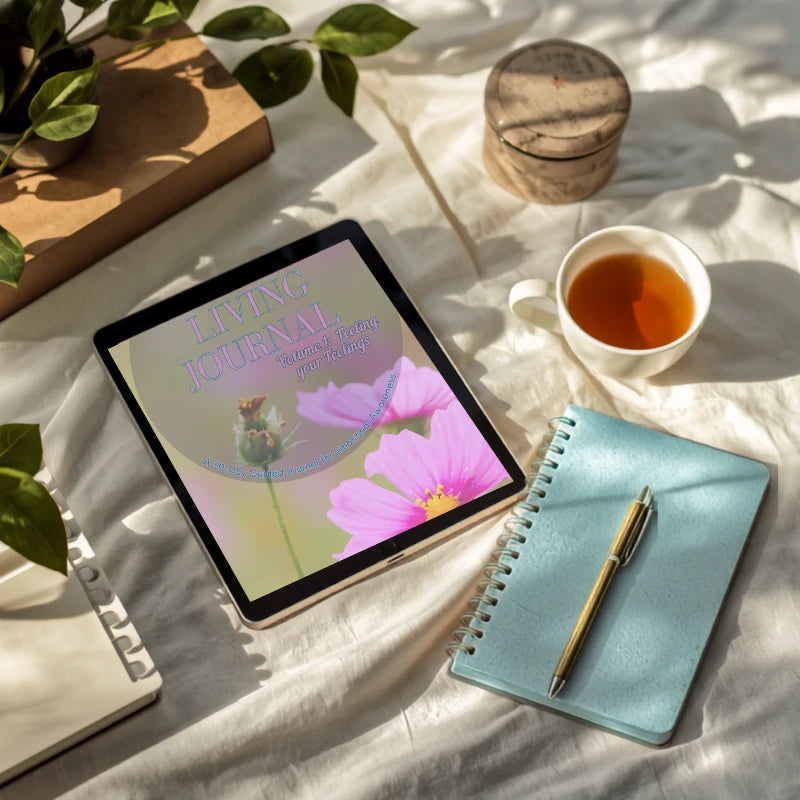 Mindful Living Journal on a tablet beside a cup of tea, teal notebook and pen on sunlit linen.